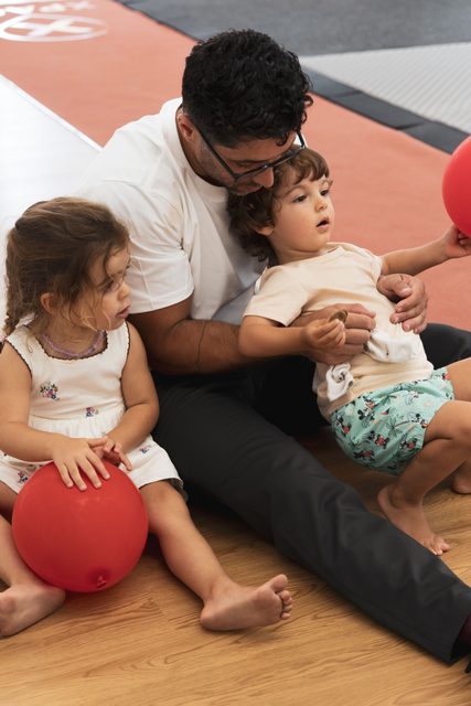 Adulto e crianças brincam com bolas no espaço de treino