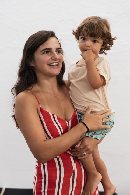 Convidada sorri com uma criança ao colo